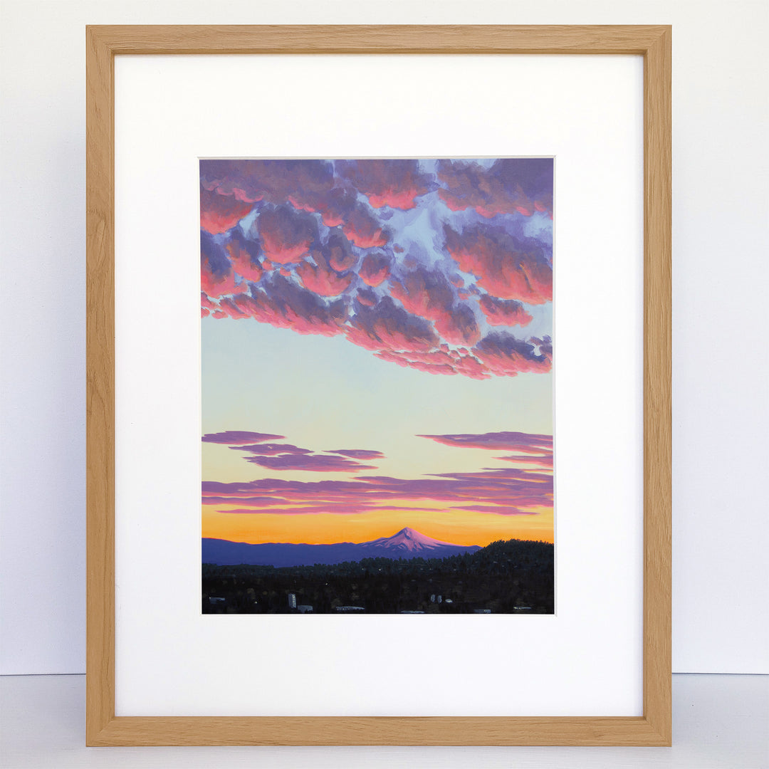A vertical art print showing sunrise over a mountain with a city in the foreground.