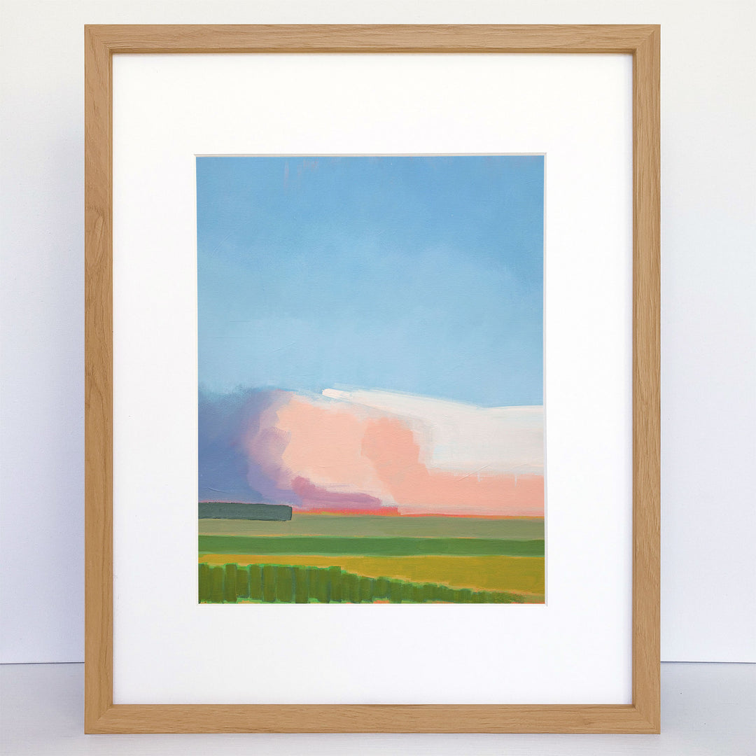 Framed art print showing an abstract landscape scene with green fields and a sunset sky.