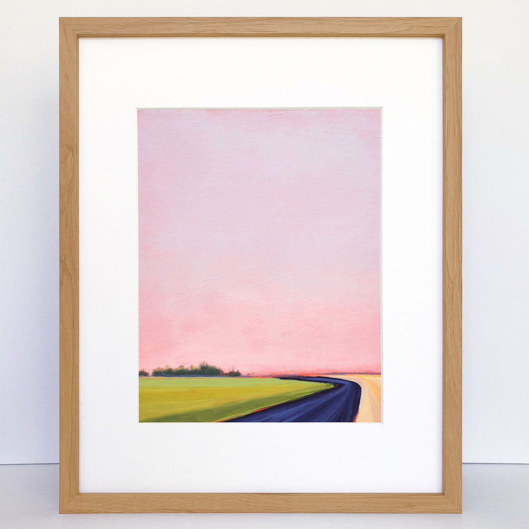 Framed art print of abstract landscape with green field and pink sky.