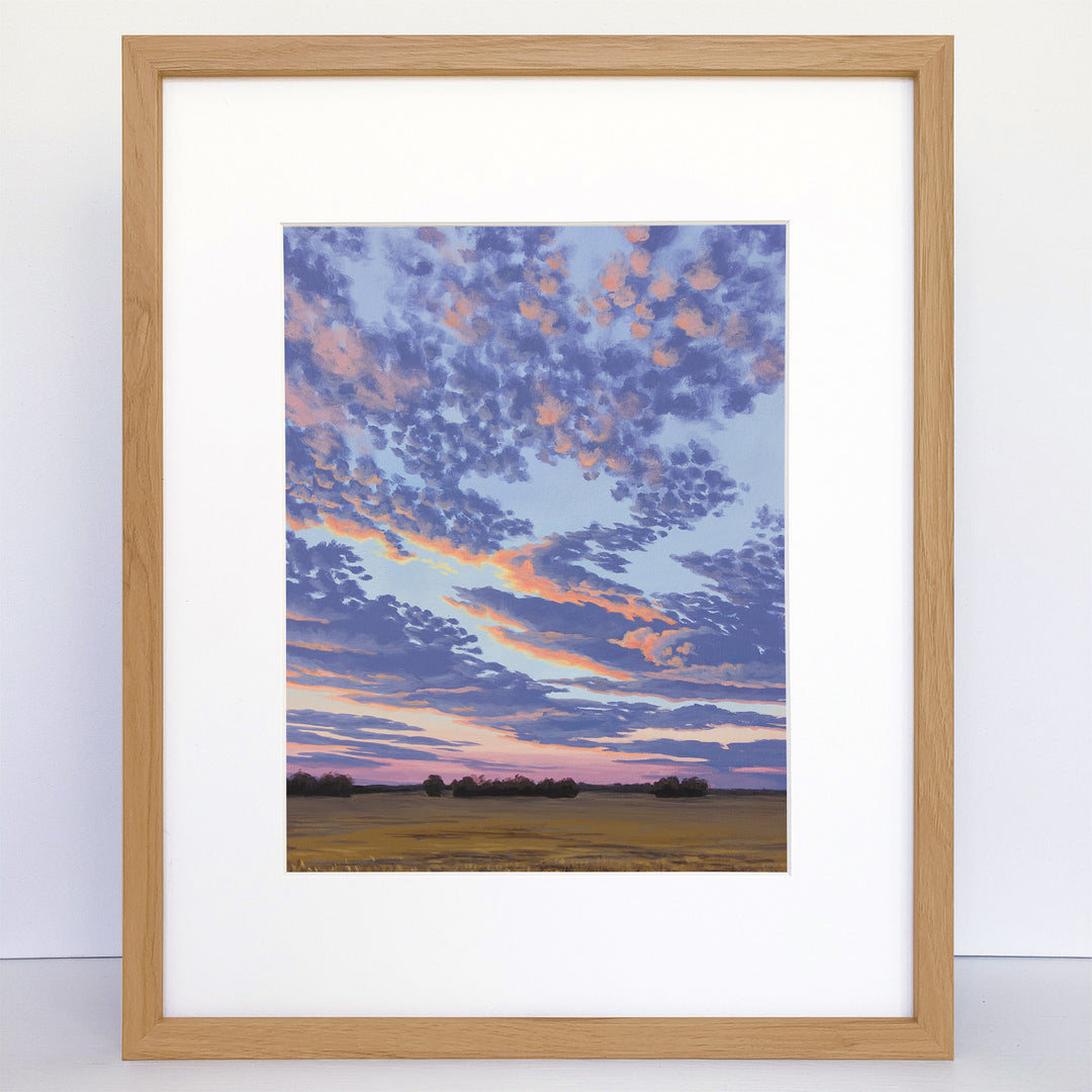 Framed art print of a prairie sunset with purple, pink, and orange clouds.