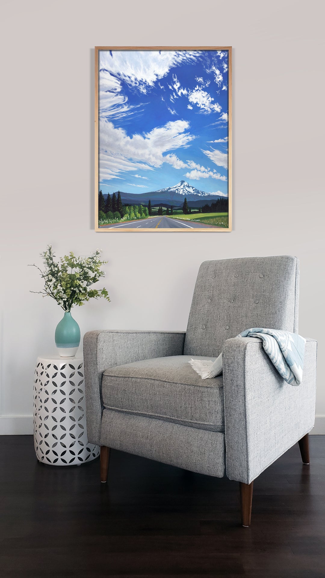 Large art print of a mountain and blue sky over a chair.